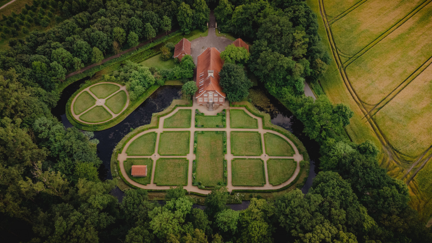 Haus R&uuml;schhaus samt Gartenanlage und Umgebung aus der Vogelperspektive. Das Grundst&uuml;ck ist von B&auml;umen und angrenzend Feldern umgeben.